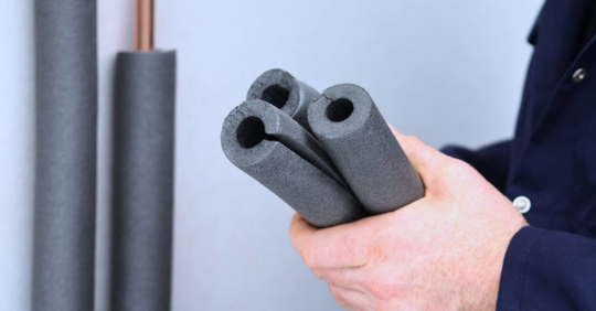 Plumber holding insulating foam for pipes.