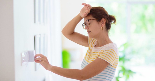 Woman adjusting thermostat on a hot day